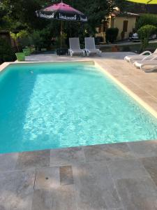 a swimming pool with two chairs and an umbrella at Les plantous de Severo in Cénac-et-Saint-Julien