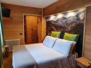 a bedroom with a large white bed with green pillows at Hotel Castor in Champoluc