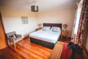 a bedroom with a bed and a chair in it at Moorpark Cottages in Barvas