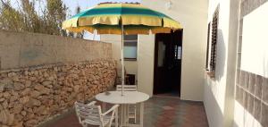 un tavolo e sedie sotto un ombrellone accanto a un muro di La Casa Dei Delfini a Lampedusa