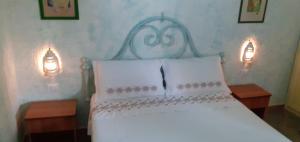 a bedroom with a white bed with two lights on it at La Casa Dei Delfini in Lampedusa