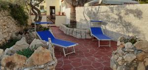 two blue chairs sitting on a patio with rocks at La Casa Dei Delfini in Lampedusa