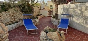 two blue chairs sitting on a patio with rocks at La Casa Dei Delfini in Lampedusa