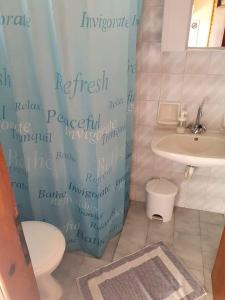 a bathroom with a shower curtain and a toilet and a sink at Skala Eresos Paradise Studios in Skala Eresou
