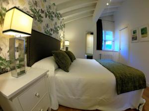 Un dormitorio con una cama blanca y una lámpara en un tocador en Finca La Casería APARTAMENTOS, en Cangas de Onís