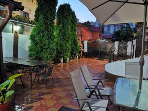 un patio con sillas, mesas y una sombrilla en Joe Hostel, en Bucarest