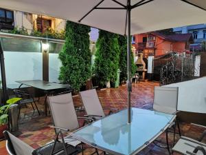 a glass table with chairs and an umbrella on a patio at Joe Hostel in Bucharest