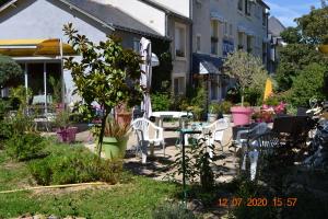 a patio with a table and chairs in a garden at Hôtel Le Castel in Brissac-Quincé