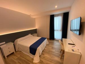 a hotel room with a bed and a desk and a television at Hostal Boutique Luz del Sol Barbate in Barbate