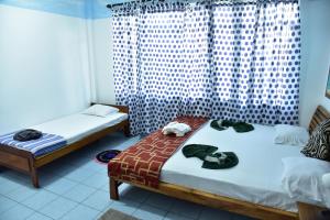 a room with two beds and a window at Hotel Happy Tuna in Hikkaduwa