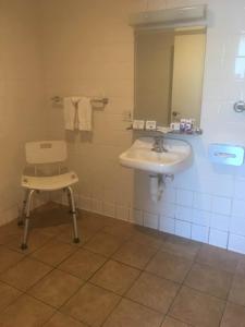 a bathroom with a sink and a chair and a mirror at Kings Inn Anaheim at The Park & Convention Center in Anaheim