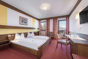 a hotel room with a bed and a desk and window at Hotel Wiedenhofer in Terento +50 photos
