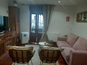 sala de estar con sofá, sillas y ventana en Apartamento El 31 de Bilbao, en Bilbao