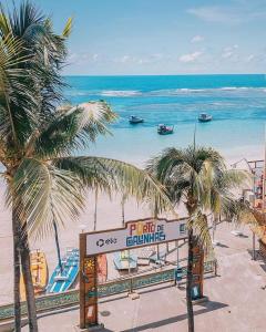 a sign on a beach with palm trees and the ocean at Flats e suites El Shaday in Porto De Galinhas