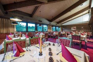 a dining room with tables and chairs and windows at Hotel Wiedenhofer in Terento