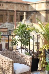 einen Korbstuhl auf einem Balkon mit Pflanzen in der Unterkunft Pànto - Rooftop boutique rooms in Palermo