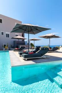 a pool with chairs and umbrellas and the ocean at Talos Luxury Suites in Kounoupidhianá