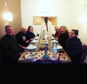 un grupo de personas sentadas alrededor de una mesa con un sacerdote en Riad Raoud Rayhane, en Essaouira