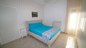 Schlafzimmer mit einem Bett mit blauer Bettwäsche und einem Fenster in der Unterkunft Mira Vico Apartments in Vico Equense