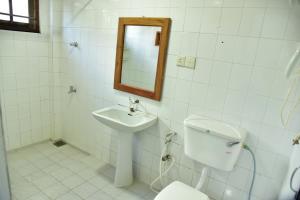 uma casa de banho com um WC, um lavatório e um espelho. em Hotel Happy Tuna em Hikkaduwa
