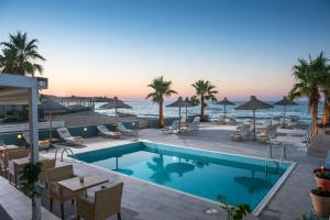 une piscine avec chaises et parasols au bord de l'océan dans l'établissement Compass beach, à Stalida