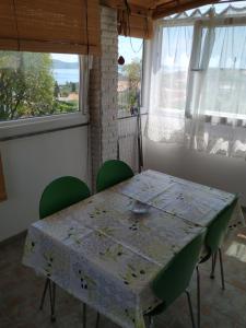 a table with green chairs in a room with a window at Apartment Anka in Savar