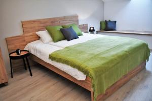 Un dormitorio con una cama grande con una manta verde. en VATUS Apartmanház Vác en Vác