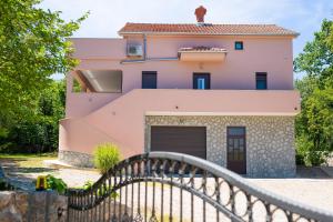 a pink house with a gate in front of it at Oak Meadow Apartment in Dobrinj +87 photos