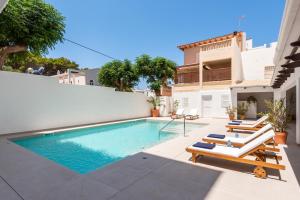 une piscine avec des chaises longues et une maison dans l'établissement Hotel Patricia Menorca, à Ciutadella