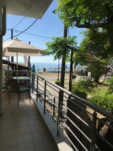 a balcony with a table and an umbrella and the beach at Luxurious Apartment Vrasna in Nea Vrasna