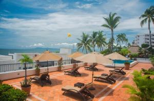 une terrasse avec des chaises et des parasols et l'océan dans l'établissement One Beach Street Zona Romantica Puerto Vallarta, à Puerto Vallarta