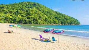 - une plage de sable avec des chaises et des parasols dans l'établissement Pousada Brigitte, à Barra do Sahy