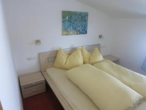 una cama con almohadas amarillas en una habitación en Haus Katharina, en Westendorf