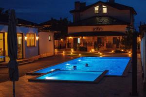 duas pessoas a nadar numa piscina à noite em Oasis family apartments em Sanzhiyka