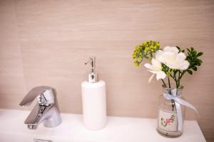 a bathroom sink with a vase with flowers in it at Covaciu aparthotel in Cluj-Napoca +35 photos
