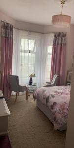 a bedroom with a bed and a chair and windows at Conlyn house in Newcastle