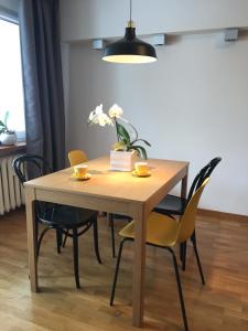 a dining room table with yellow chairs and a light fixture at Fregata Apartment Gdynia in Gdynia