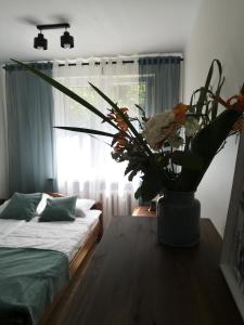 ein Wohnzimmer mit einem Tisch und einer Blumenvase in der Unterkunft Apartament przy Starówce in Sandomierz
