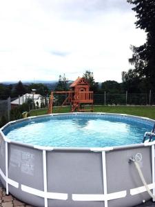 a large swimming pool with a playground in the background at Holiday Home Smržovka in Smržovka