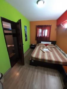 a room with a wooden bed in a room with green walls at Casa Rebeca in Neptun