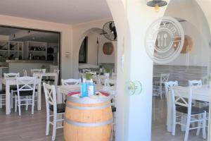 a restaurant with white tables and chairs and a barrel at Castro Hotel in Amoudara Herakliou