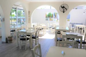 a restaurant with white tables and chairs and windows at Castro Hotel in Amoudara Herakliou