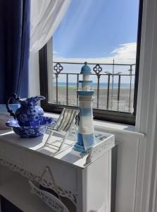 a table with a lighthouse and a window with a view of the beach at Conlyn house in Newcastle