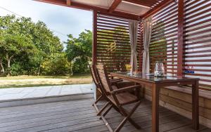 a wooden table and chair on a deck with a window at Happy Apartments Baška in Baška