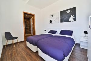 a bedroom with a large purple bed and a chair at Il-Pipa in Għasri