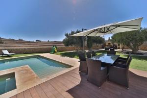 a table with an umbrella next to a swimming pool at Il-Pipa in Għasri