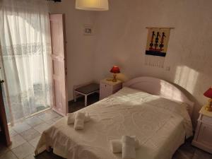 a bedroom with a white bed with towels on it at Porto Sikinos Hotel in Alopronia