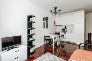 ポルトにあるESM Rental - Santa Catarina Cozy Apartmentの白いキャビネットとテーブル付きのキッチンが備わります。