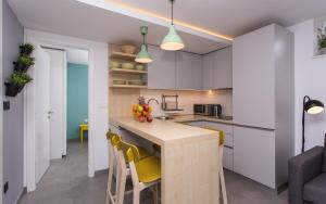 a kitchen with white cabinets and a counter with yellow chairs at Happy Apartments Baška in Baška +60 photos