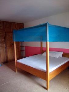 a bedroom with a bed with a blue canopy at Auberge Cœur Océan in Joal-Fadiout